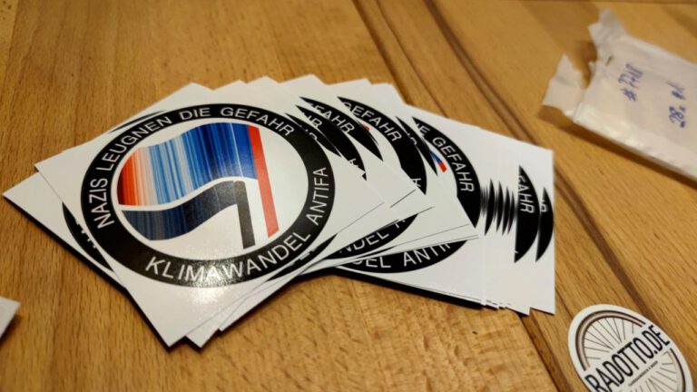 Frisch eingetroffene Sticker Klimaschutz ist AntiFa von radotto liegen auf einem Holztisch