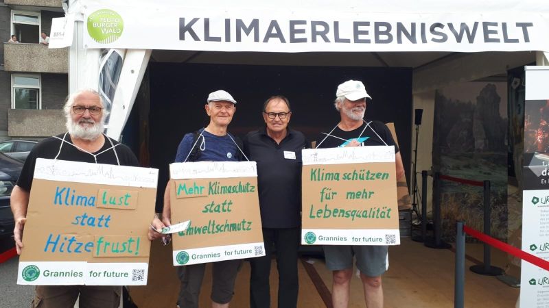 NRW-Tag in Köln - Grannies for Future präsentieren ihre Sandwichlauf-Schilder. 3 Grannies for Future präsentieren zusammen mit Ewald Lienen - bekannter Fußballer und Trainer (u.a. von Bor. Mönchengladbach und dem FC Kölle )  drei Schilder mit der Aufschrift: Klimalust statt Hitzefrust Mehr Klimaschutz statt Umweltschmutz Klima schützen für mehr Lebensqualität