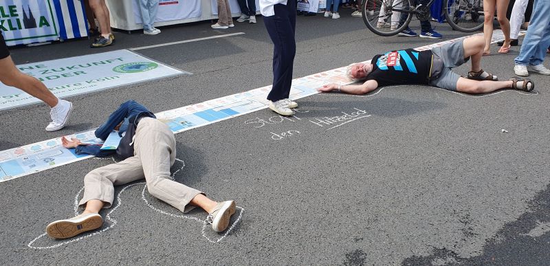NRW-Tag in Köln - Grannies for Future und Health for Future haben Spuren auf der Straße hinterlassen: Zwei Menschen liegen auf der Staße. Stop den Hitzetod!