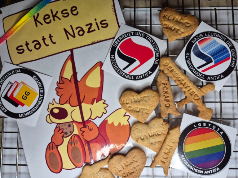 Der gezeichnete Fuchs von Fuchskind hält ein Demoschild mit der Aufschrift "Kekse statt Nazis" in die Luft. Das Bild wird umrahmt mit Keksen in verschiedenen Formen. Darauf gestempelt finden sich die Schriftzüge Demokratie, Klimaschutz und FCKAFD. Verschiedene AntiFa-Aufkleber von Radotto ergänzen das Bild. U.a. "Überreizt und trotzdem da - hochsensible AntiFa", "Nazis leugnen die Gefahr - Klimschutz ist AntiFa", "Artikel 1 und deshalb da - Menschenrecht ist AntiFa", "LGBTQIA - Regenbogen AntiFa"