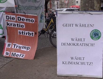"Wählt Klimaschutz" - Infostand und Kundgebung am 22.02.25 auf dem Chlodwigplatz in Köln Zwei Laufschilder sind zu sehen. Links mit der Aufschrift: "Die Demokratie stirbt # Trump #Merz", Rechts mit der Aufschrift "Geht wählen, Wählt demokratisch, wählt Klimaschutz" und dem Logo der Parents for Future Köln Foto: Ulla Kellerwessel