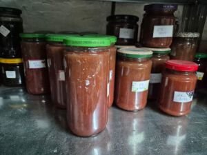 In einem Vorratsregal aus Blech stehen mehrere selbst gekochte Marmelanden, abgepackt in Gläser.